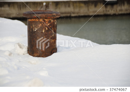 站立在與雪的一個碼頭的停泊柱子。 站立在與雪的一個碼頭的停泊柱子。 37474067