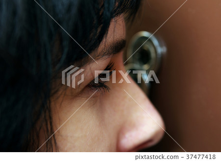 Closeup of woman looking through peephole Closeup of woman looking through peephole 37477418
