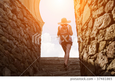 Girl in a hat with a backpack climbs the stairs 37481865