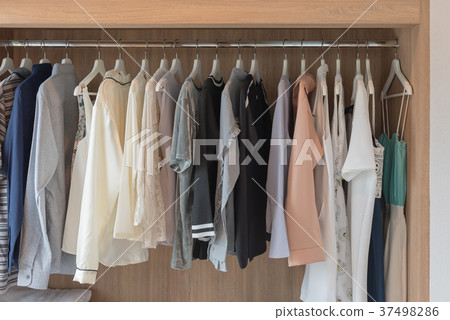 wooden closet with clothes hanging 37498286