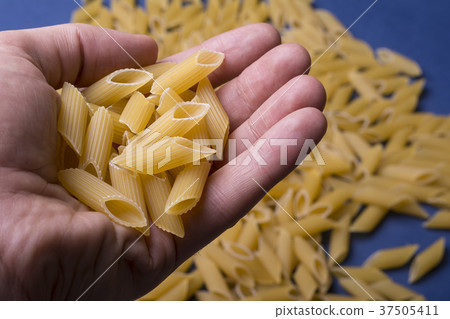 Hand holding dry tubular penne pasta Hand holding dry tubular penne pasta 37505411
