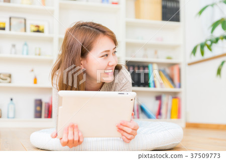 觀看一種片劑的婦女在屋子裡 觀看一種片劑的婦女在屋子裡 37509773