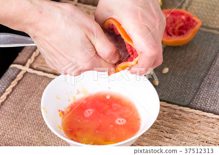 Squeezing grapefriuit with metal spoon. 37512313