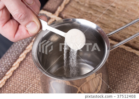 Adding powdered gelatin to water. 37512408