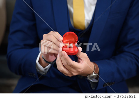 The groom is showing  a wedding ring 37512651