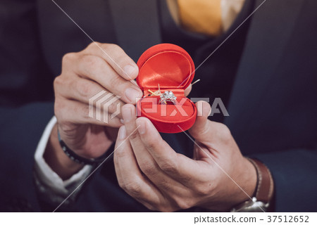 The groom is showing  a wedding ring  37512652