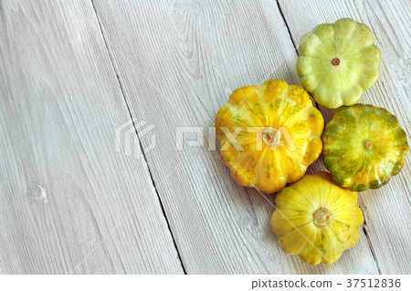 Four yellow and green bush pumpkins on white wood Four yellow and green bush pumpkins on white wood 37512836