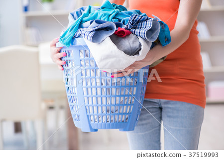 Stressed woman doing laundry at home 37519993