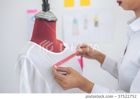Young woman dressmaker or designer working as measuring for clot Young woman dressmaker or designer working as measuring for clot 37522752