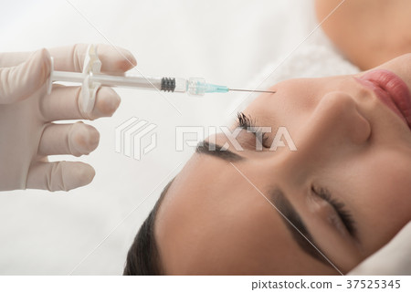 Surgeon injecting anti-aging liquid into female Surgeon injecting anti-aging liquid into female 37525345