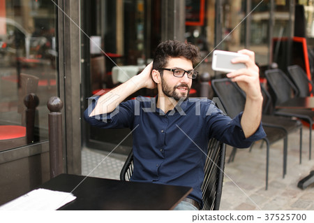 Arabic man making selfie with smartphone at cafe Arabic man making selfie with smartphone at cafe 37525700