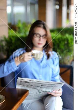 Charming woman reading newspaper at restaurant and Charming woman reading newspaper at restaurant and 37525776