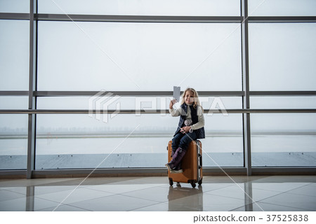 Smiling girl resting on big suitcase Smiling girl resting on big suitcase 37525838