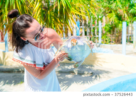 Tourist woman with sea turtle in the hands in Tourist woman with sea turtle in the hands in 37526443