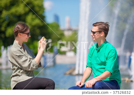 Young girl taking a picture of boyfriend while Young girl taking a picture of boyfriend while 37526832