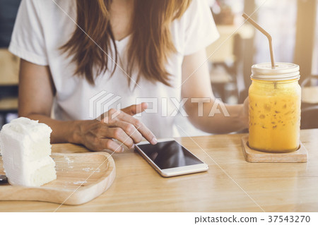 Young woman using smart phone and eating cake Young woman using smart phone and eating cake 37543270