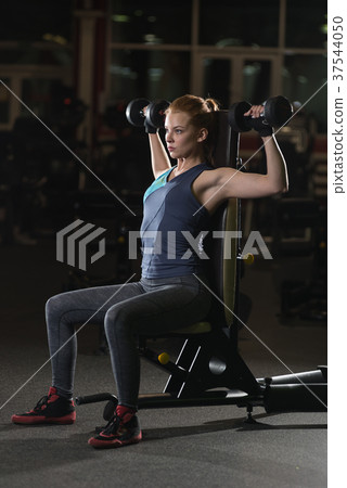 Young woman lifting the dumbbells Young woman lifting the dumbbells 37544050