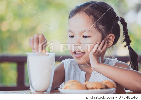 asian little child girl eating cookie with milk asian little child girl eating cookie with milk 37548140