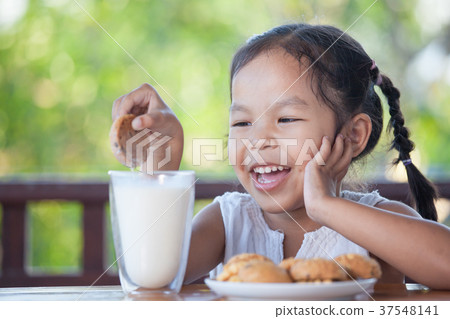 asian little child girl eating cookie with milk asian little child girl eating cookie with milk 37548141