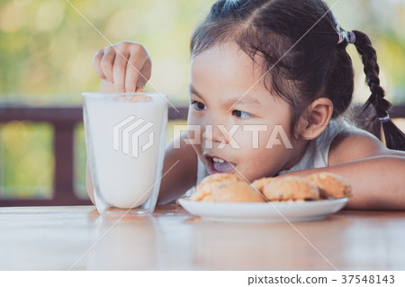 asian little child girl eating cookie with milk 37548143