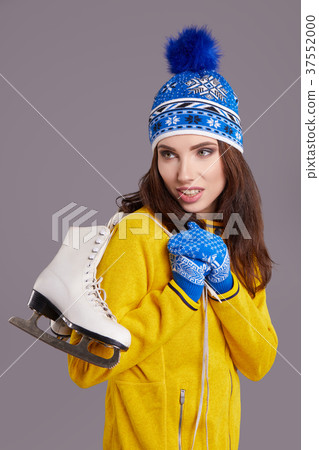 Smiling young woman carrying a pair of ice skates 37552000