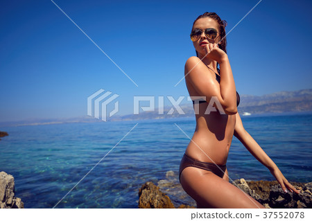 Young adult slim woman in 20s posing on rocks on adriatic sea co Young adult slim woman in 20s posing on rocks on adriatic sea co 37552078