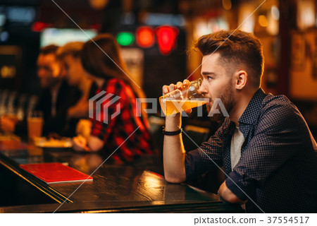 Man drinks beer at the bar counter in a sport pub Man drinks beer at the bar counter in a sport pub 37554517