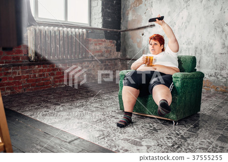 Overweight woman watches TV, bulimic, fatty Overweight woman watches TV, bulimic, fatty 37555255