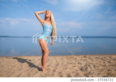 Blonde girl in a blue suit is doing yoga on beach 37556715