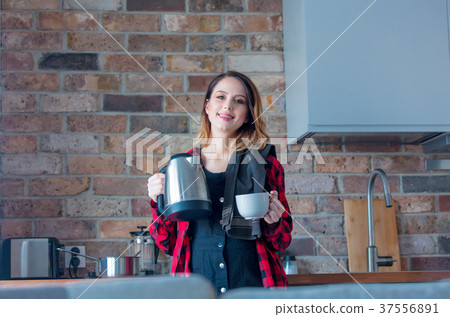 Young redhead pregnant woman with kittle and cup Young redhead pregnant woman with kittle and cup 37556891
