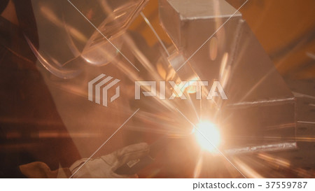 The welder welds metal parts at the plant 37559787