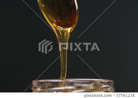 scooping organic honey with spoon from glass jar scooping organic honey with spoon from glass jar 37561238