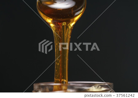 scooping organic honey with spoon from glass jar scooping organic honey with spoon from glass jar 37561242
