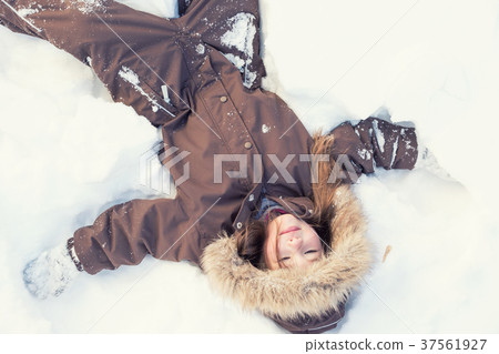 Beautiful little girl making a snow angel 37561927