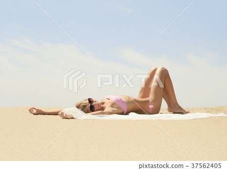 Tanned young female relaxing on the beach Tanned young female relaxing on the beach 37562405