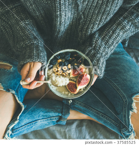Woman in shabby jeans and sweater eating breakfast Woman in shabby jeans and sweater eating breakfast 37585525