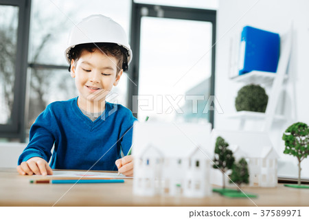 Little boy in hard hat drawing at the table 37589971