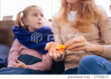 Sad little sick girl taking pills 37590673