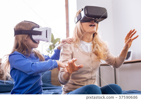 Concentrated mother and her kid wearing VR headset 37590686