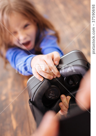 Irritated girl taking away VR helmet Irritated girl taking away VR helmet 37590698