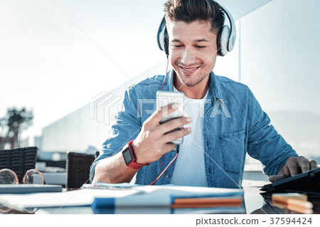 Beaming student listening to music outdoors Beaming student listening to music outdoors 37594424