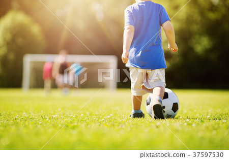 Little boy playing football on the field with Little boy playing football on the field with 37597530