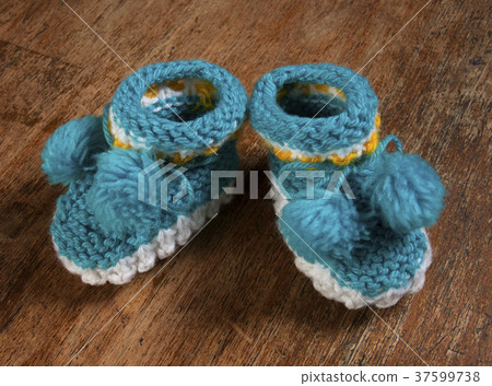 Colorful knitted baby booties on a wooden board. Colorful knitted baby booties on a wooden board. 37599738