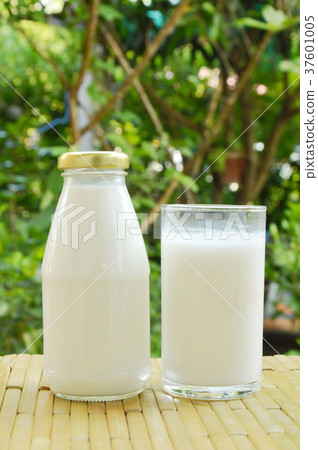bottle and glass of milk on bamboo mat in park 37601005