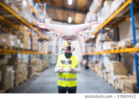 Man with drone in a warehouse. Man with drone in a warehouse. 37603413