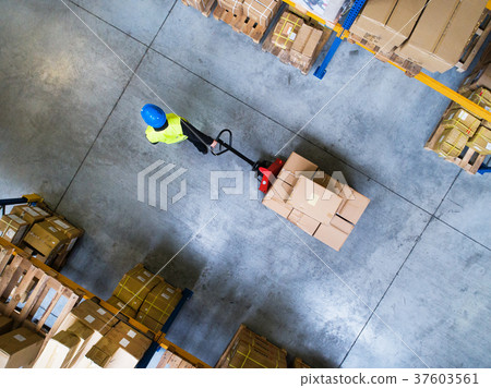 Male warehouse worker pulling a pallet truck. 37603561