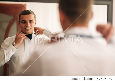 The groom is dressed at home in a suit. Cute groom The groom is dressed at home in a suit. Cute groom 37603979