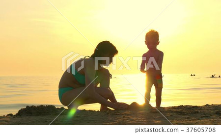 Happy mom and child playing on the beach in the Happy mom and child playing on the beach in the 37605708