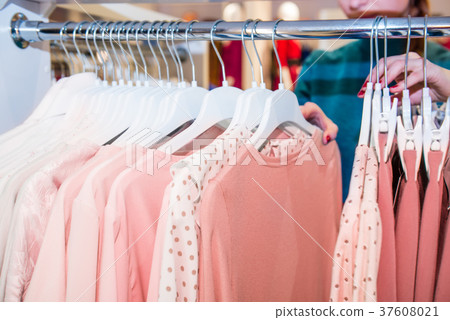 searching through hangers with clothes in store searching through hangers with clothes in store 37608021