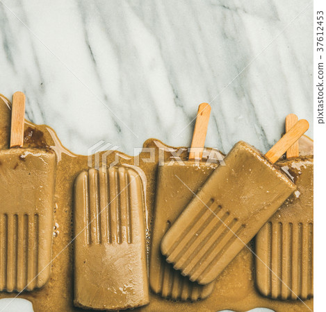 Flatlay of melting coffee latte popsicles, copy 37612453